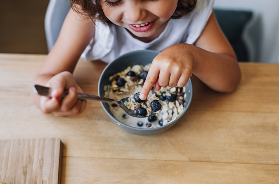 Young girl eating oatmeal with blueberries