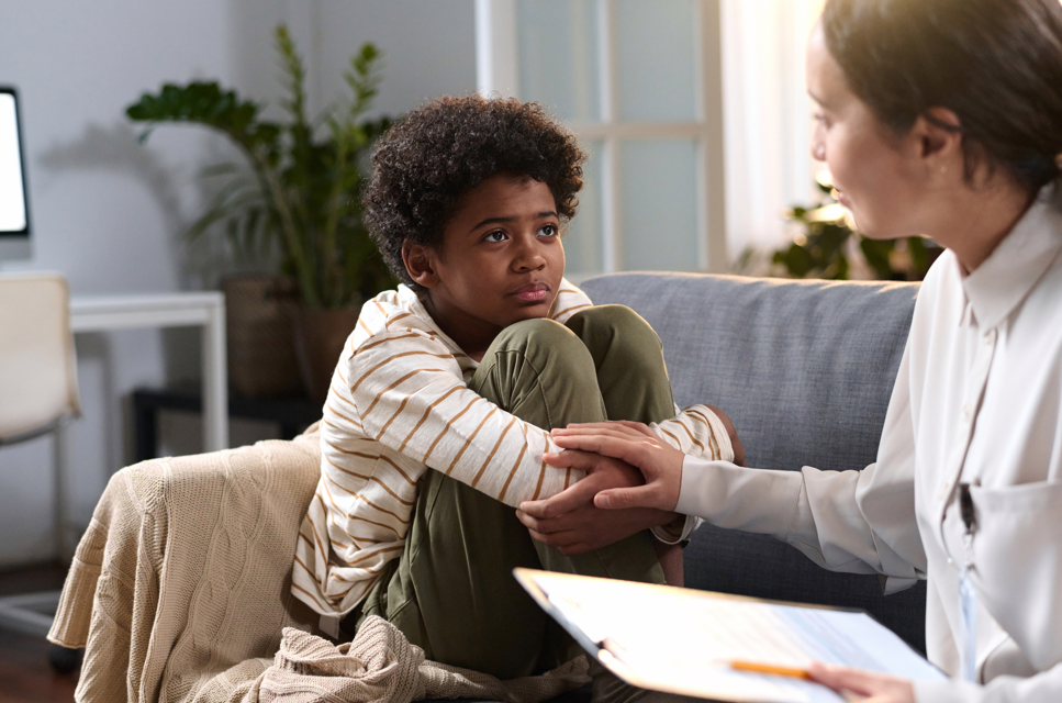 Young boy sitting on couch with therapist