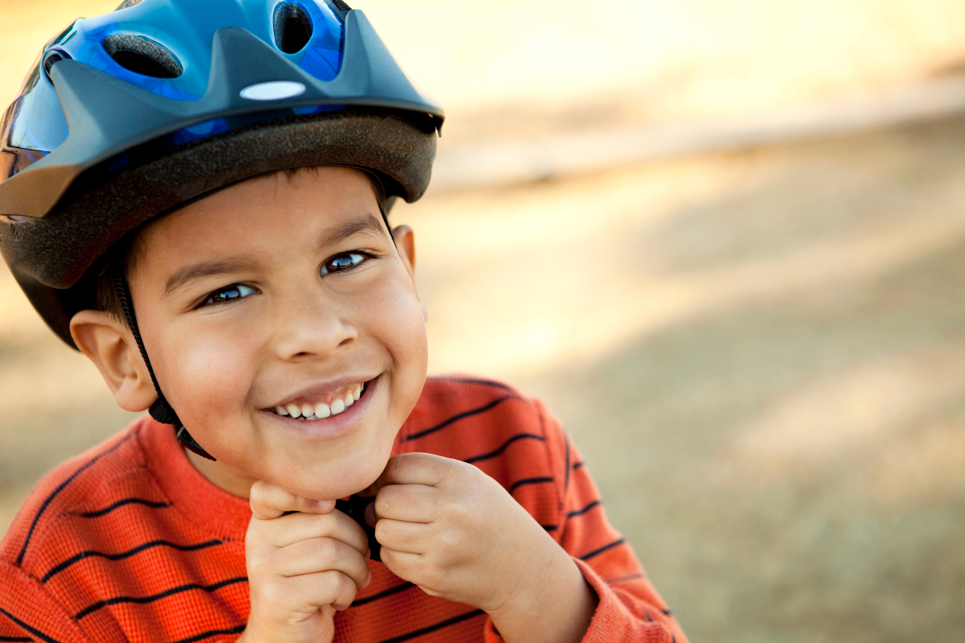 Young boy fastening bike helmet
