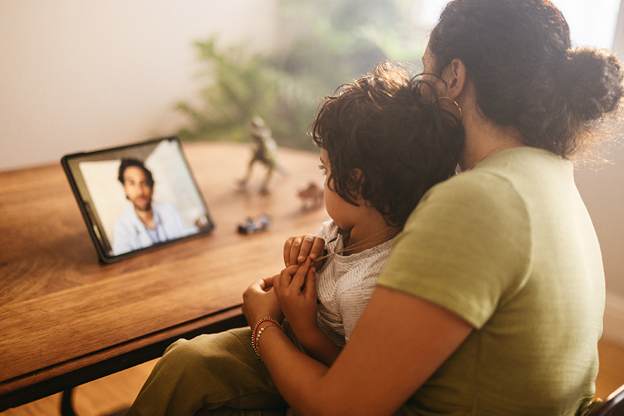 Mother and child video calling their family doctor at home.