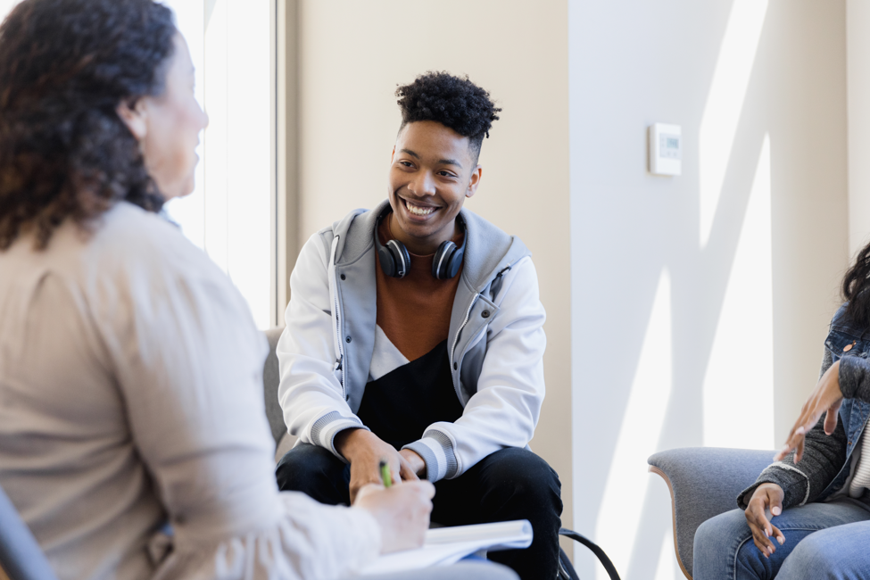 Young man speaking with counseling in group therapy session.