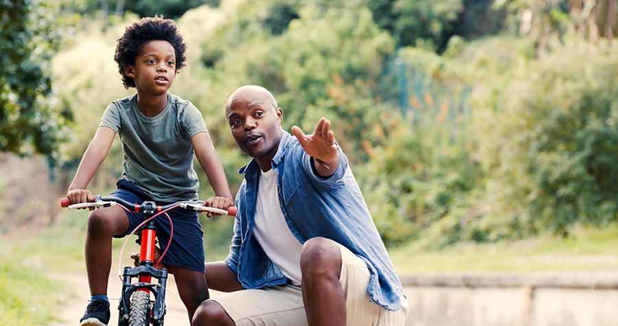 Dad helping son learn to ride bike.