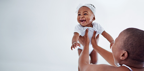 Mom lifting infant with both arms above her head.