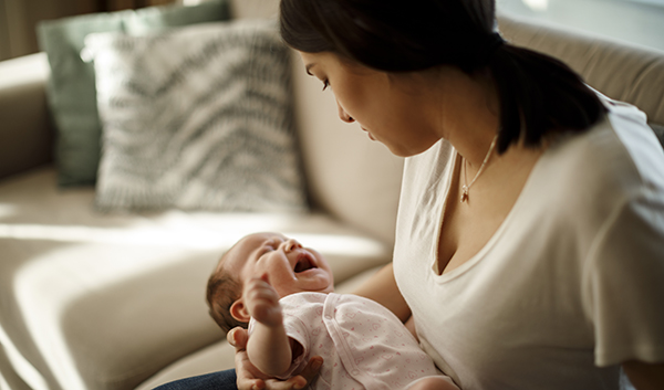 Mom holding crying infant.