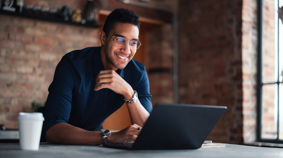 Young man looking at laptop with happy expression on his face.