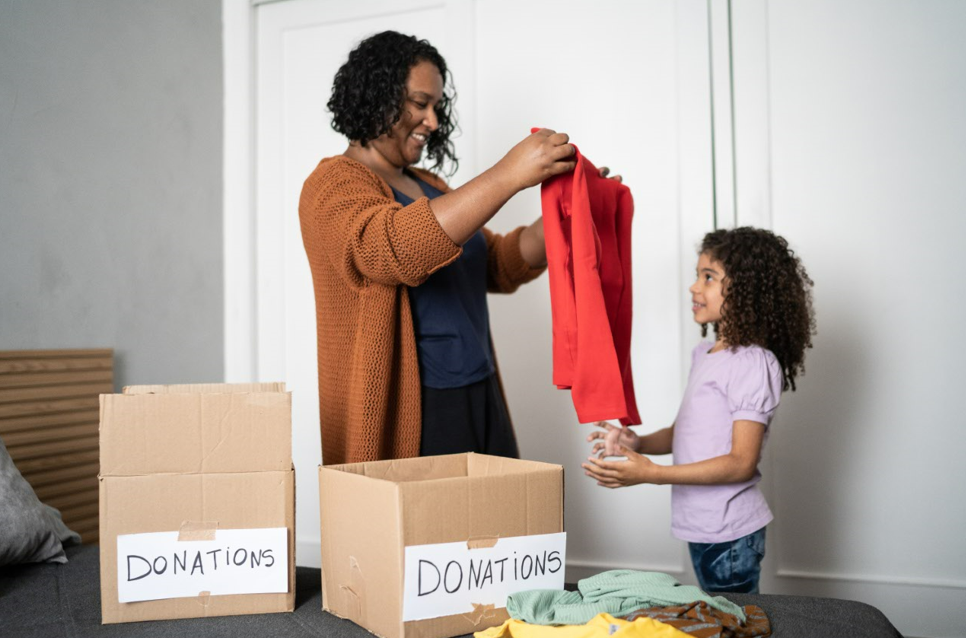 Mom and young daughter sorting clothes into donation piles.
