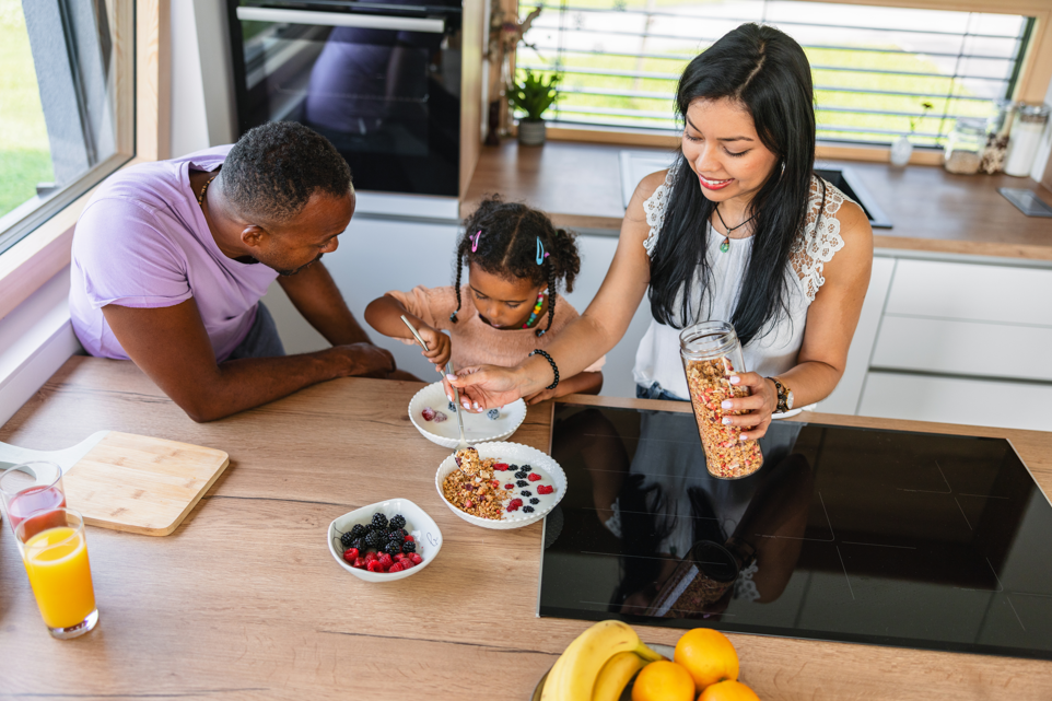 Mom, Dad and young child at table eating oatmeal.