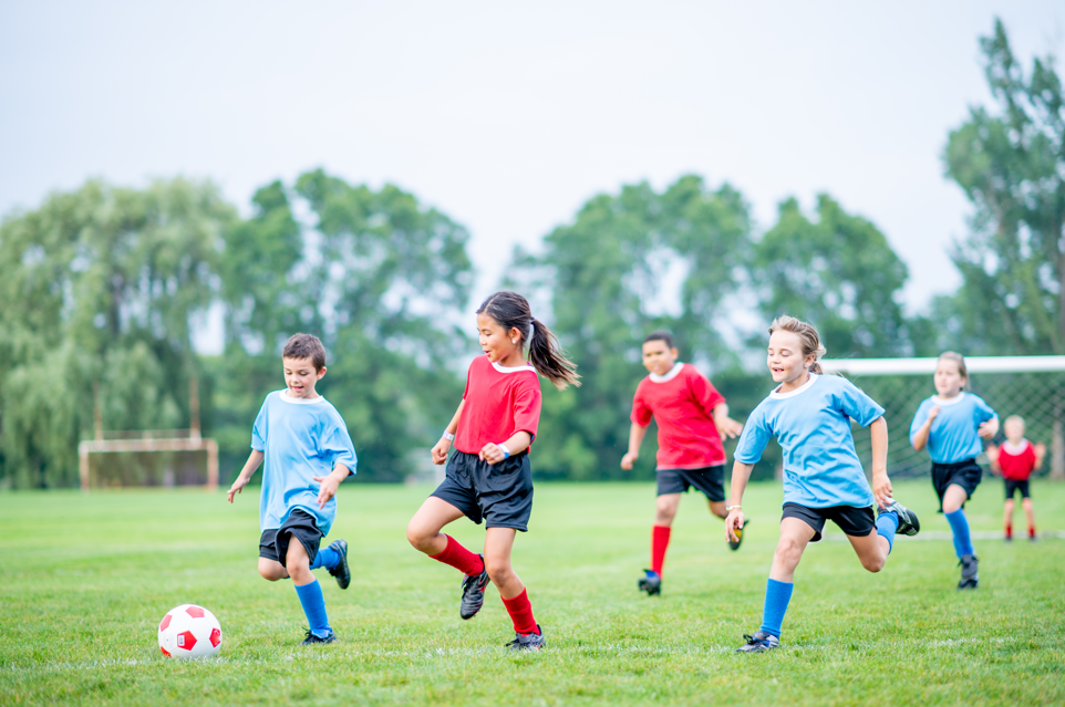 Young children playing soccer outside.
