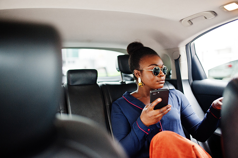 Young woman on phone in back seat of car