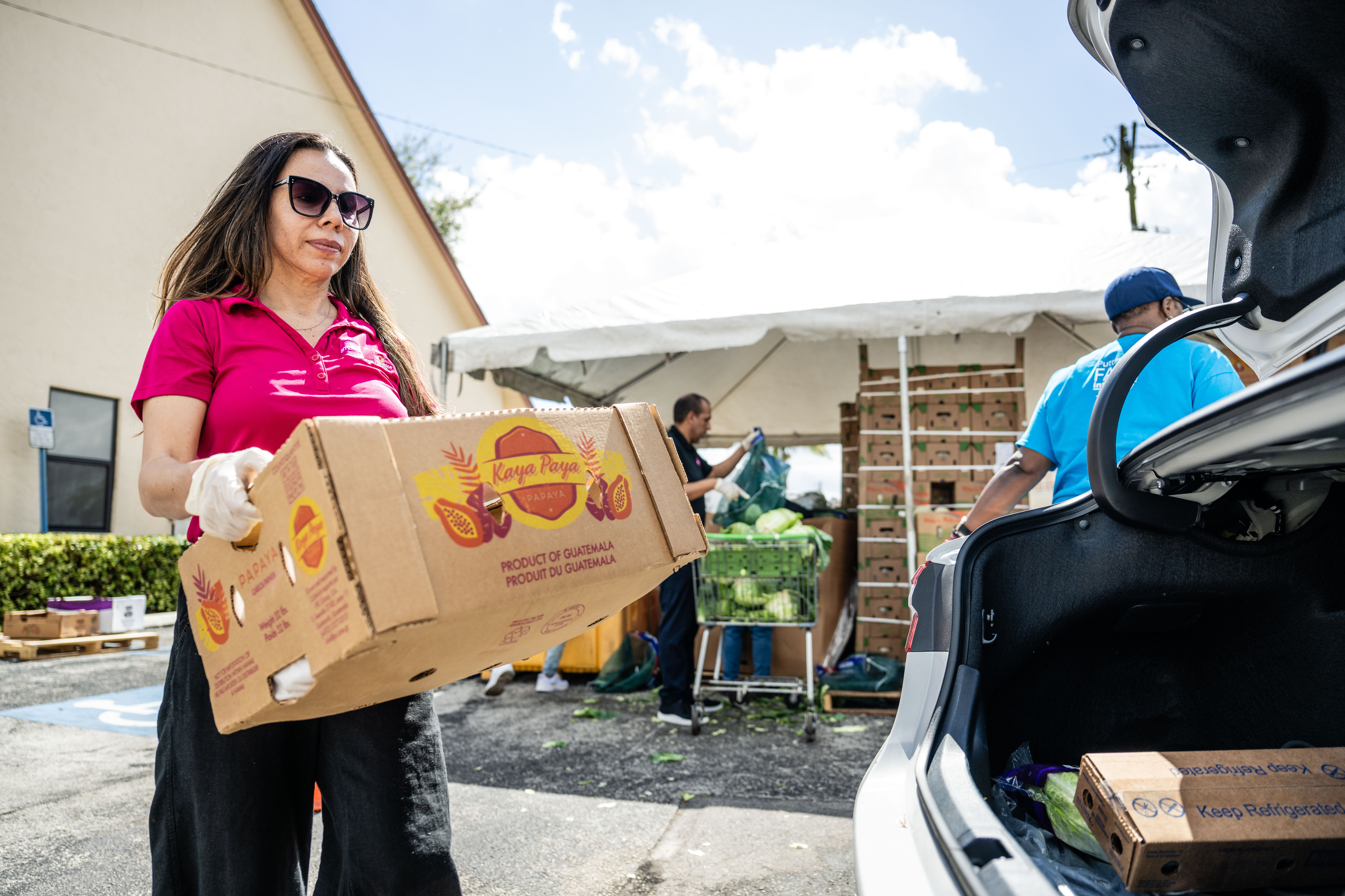 Ambetter from Sunshine Health team member loads box of food into car.
